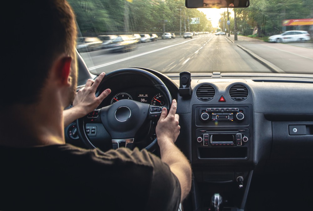 A male driver drives at speed through the streets of the city, a view from inside the car.