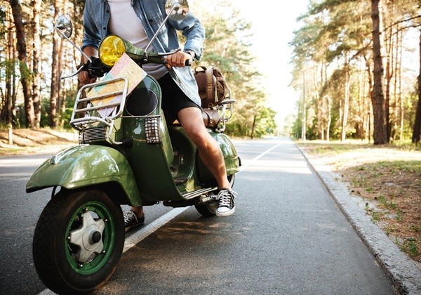 Cropped picture of young man on scooter outdoors.